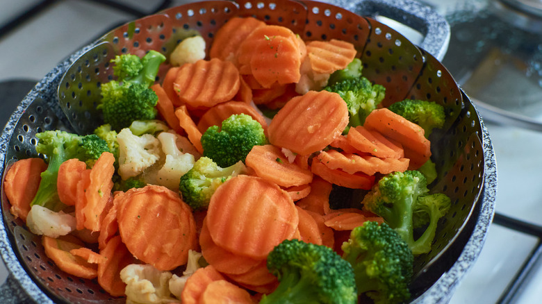 Steamed broccoli, carrots, and cauliflower in a metal steamer basket