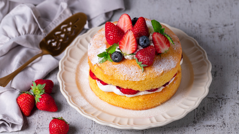 layered cake on a platter with serving spoon and fruit