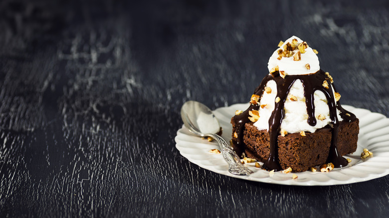 hot fudge brownie sundae with nuts on a white plate