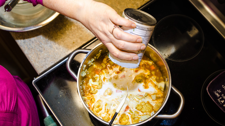 Adding coconut milk to a soup