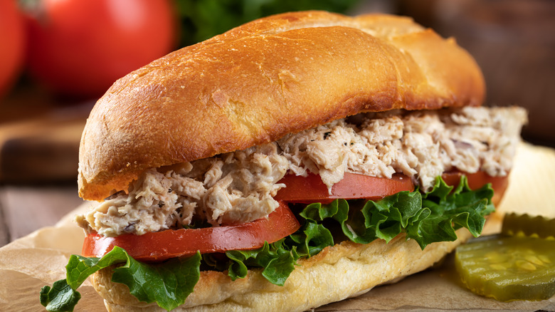 Tuna salad hero sandwich with lettuce, tomatoes, and pickles