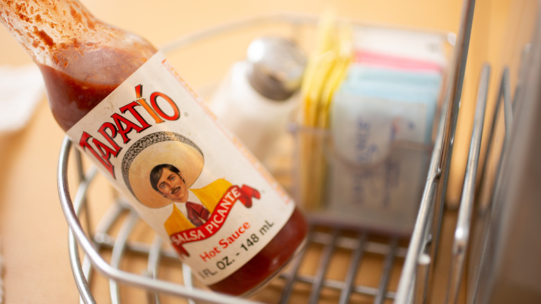 A closeup view of bottle of Tapatio hot sauce in a condiment tray, seen at a local restaurant