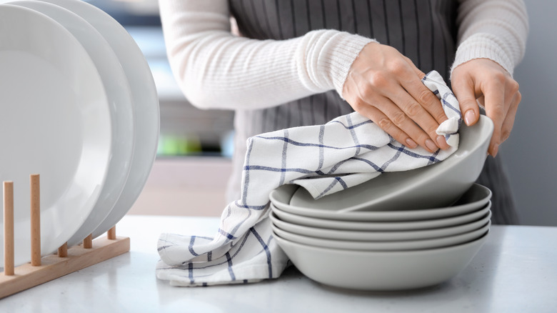 A person dries a plate with a kitchen towel