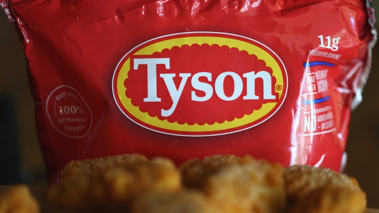 A focus on the Tyson brand label on a red bag behind blurred chicken nuggets