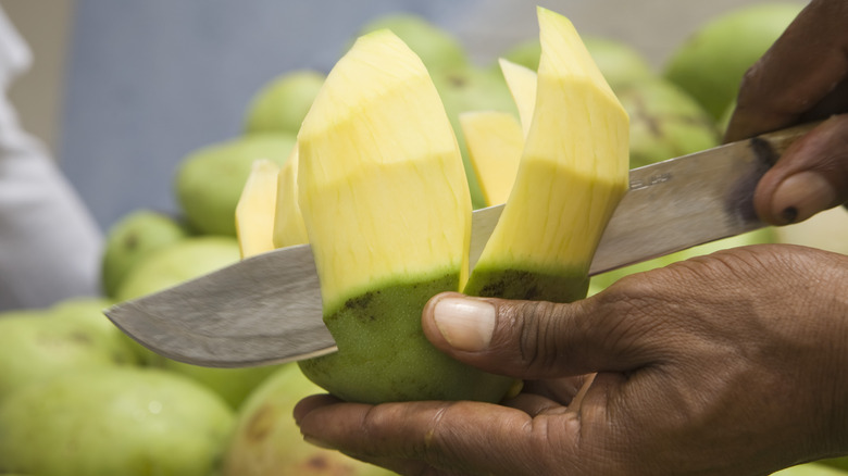 Person slicing green mango