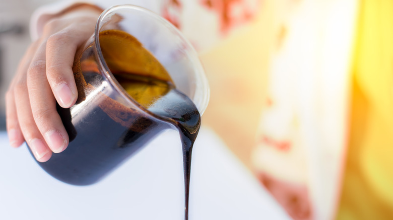 Person pouring molasses from beaker