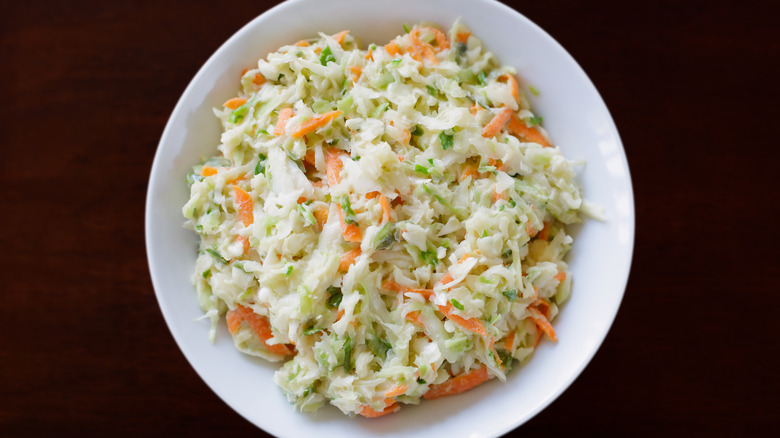 White bowl filled with coleslaw on brown table
