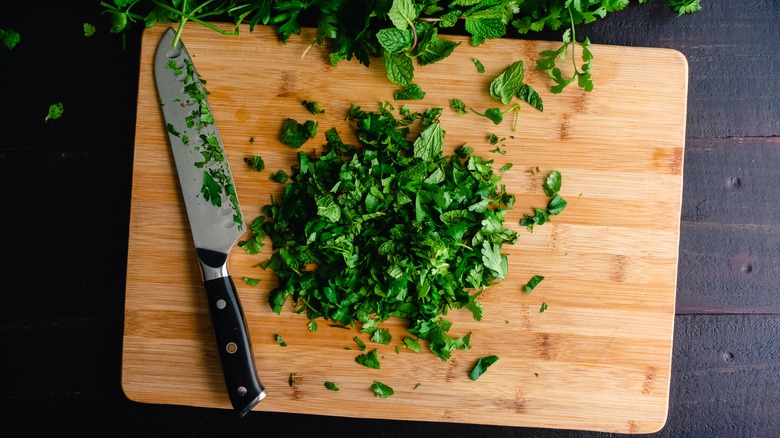 knife with chopped herbs on cutting board