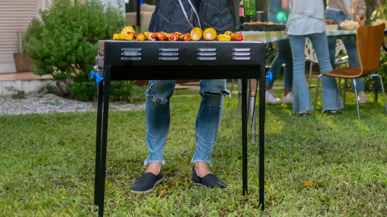 A grill that's a little lopsided on a green lawn