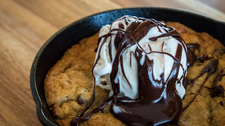 Cookie in a skillet pan topped with ice cream and chocolate sauce