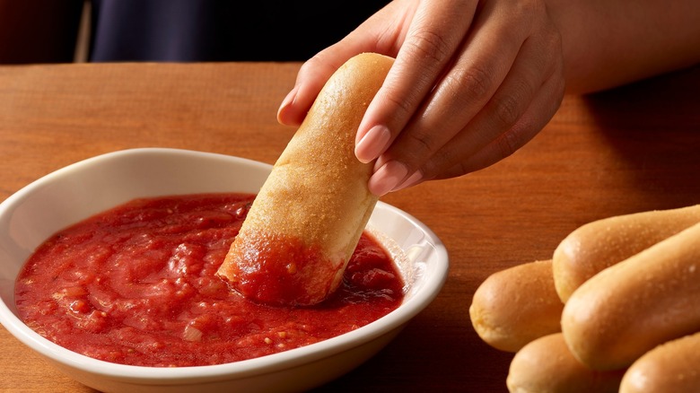 Person dipping Olive Garden breadstick