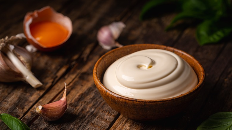 Mayonnaise in brown ceramic bowl on wooden table