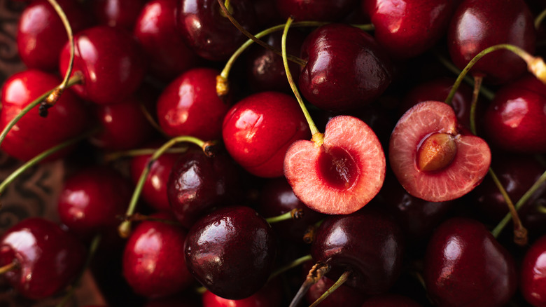 pile of halved and whole cherries with stems on