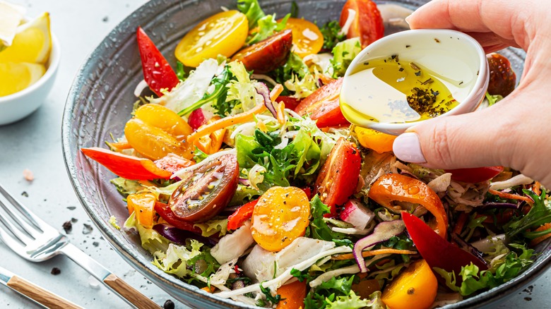 adding dressing to colorful salad