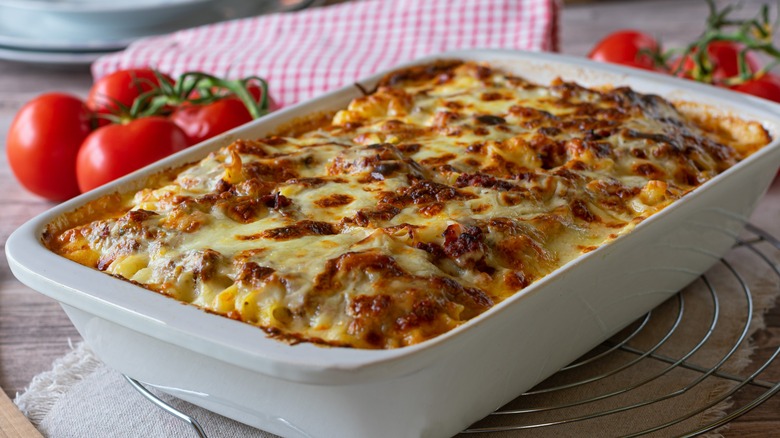 cheesy casserole in a pan surrounded by tomatoes
