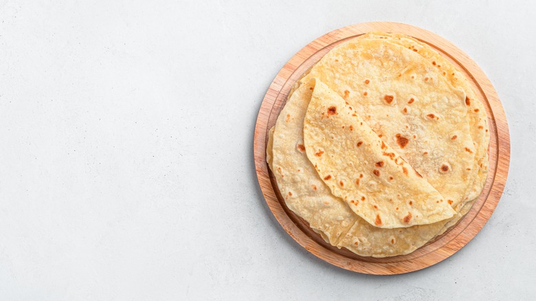Stack of flour tortillas on a wooden plate