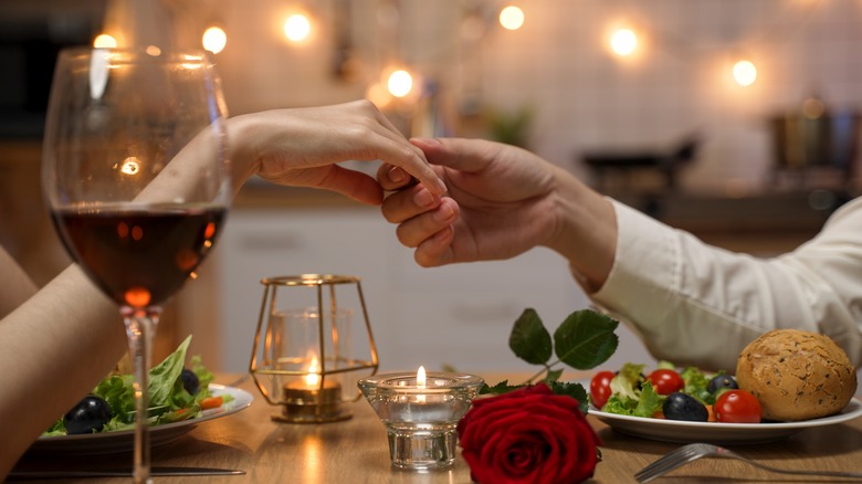 Couple hold hands over dinner