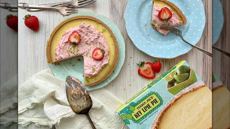 A promotional image for Trader Joe's Key Lime Pie, topped with a whipped strawberry cream and strawberries