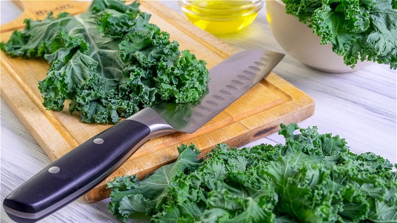 Raw kale on cutting board with knife