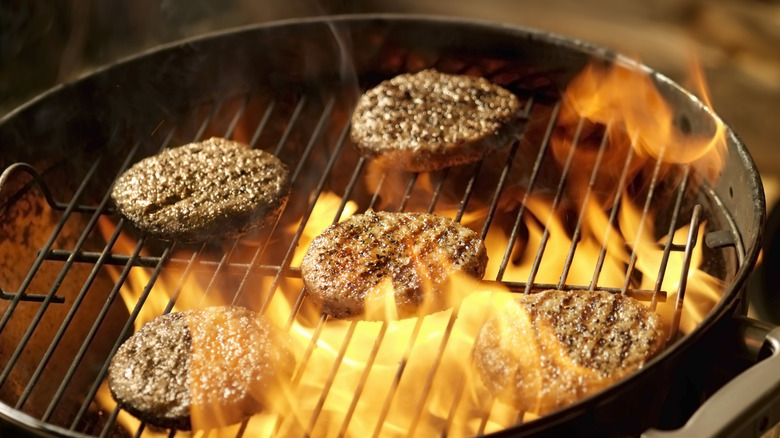 Turkey meat patties on flaming grill