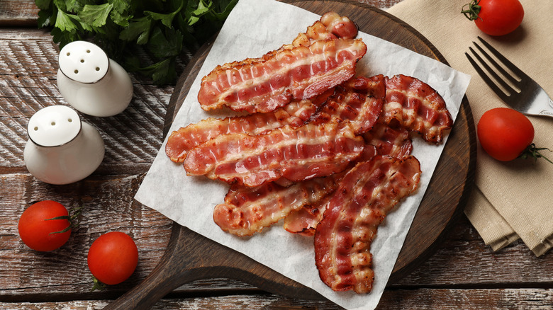 Thin fried bacon on a walnut cutting board