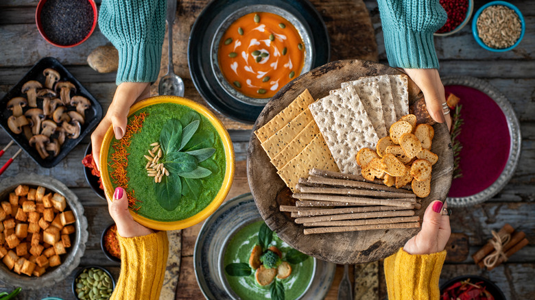 Two people at a table with various soups and crackers