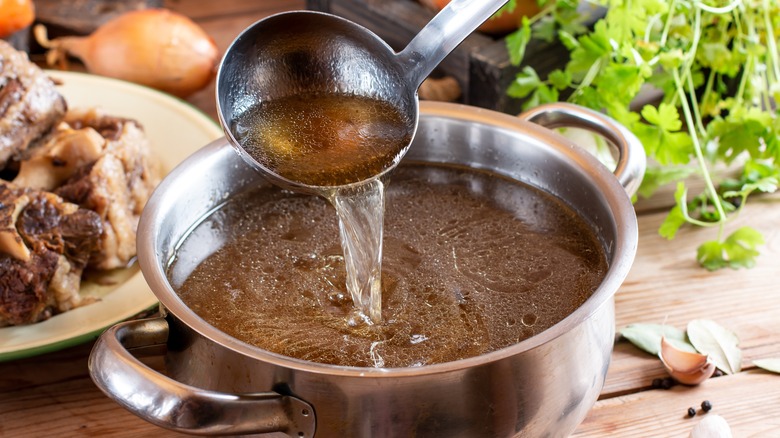 Beef broth ladled into pot
