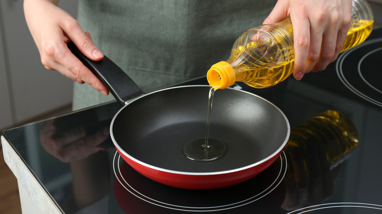 Hands pouring oil into non-stick pan