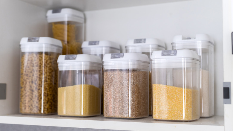 Various plastic containers filled with dry goods on a shelf