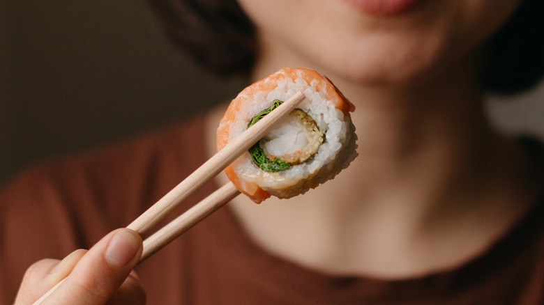 woman eating sushi with chopsticks