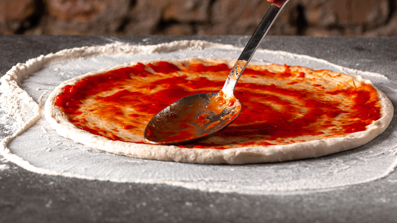 Tomato sauce spread on pizza dough