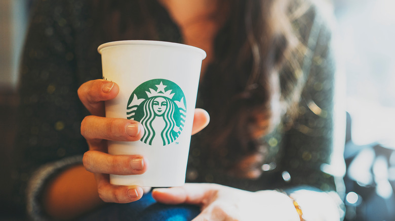 woman holding Starbucks coffee cup