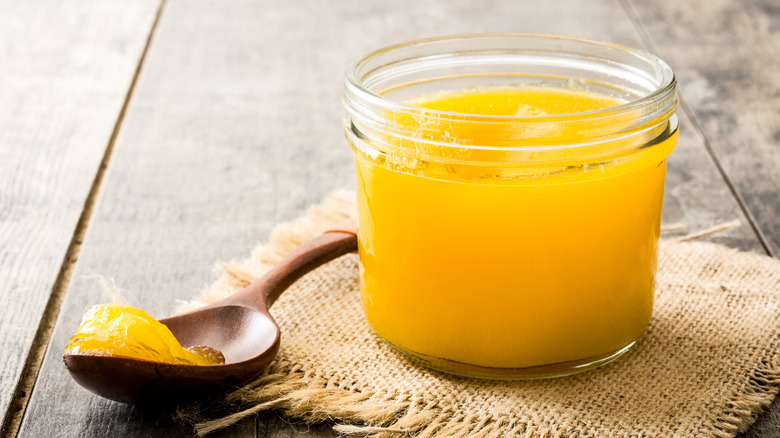 Spoonful of ghee from a glass jar.