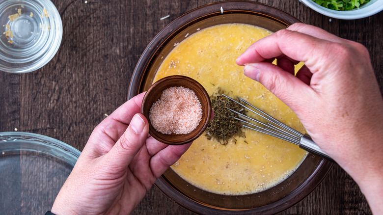 hands adding salt to bowl