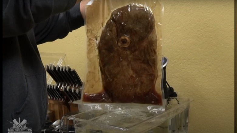 Sous vide Tom and Jerry Steak in plastic bag, being held above tub of water