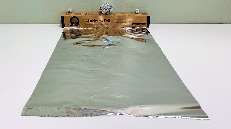 A box of If You Care Aluminum Foil next to a sheet and some balls of aluminum foil