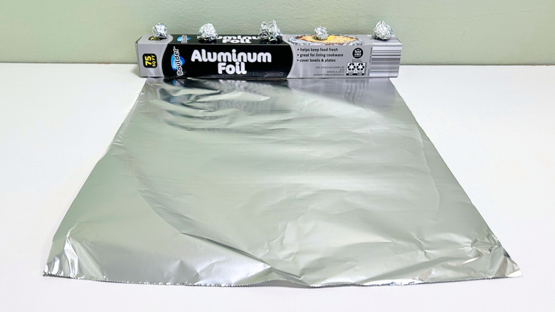 A box of Boulder Aluminum Foil next to a sheet and some balls of aluminum foil