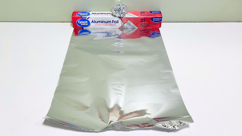 A box of Great Value Aluminum Foil next to a sheet and some balls of aluminum foil