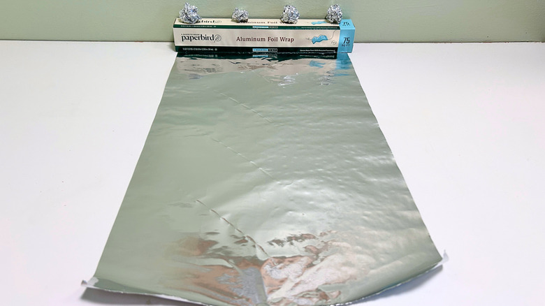A box of Paperbird Aluminum Foil Wrap next to a sheet and some balls of aluminum foil