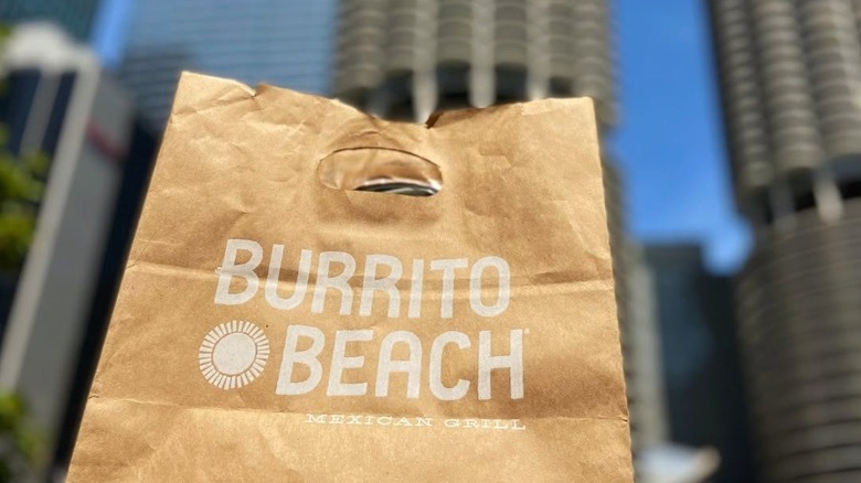 Burrito Beach paper takeout bag with skyscrapers in the background