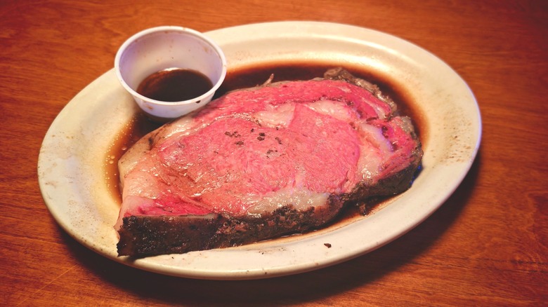 Texas Roadhouse prime rib on a plate with cup of au jus