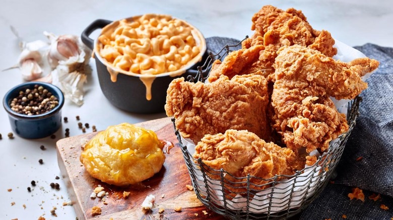 a table full of Krispy Krunch fried chicken pieces, a bowl of mac and cheese, a honey butter biscuit, and a ramekin of peppercorns