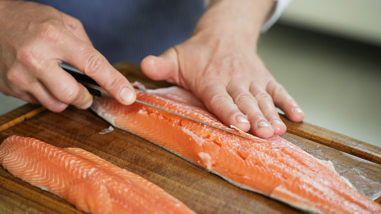A cook's hands are shown fileting Arctic char