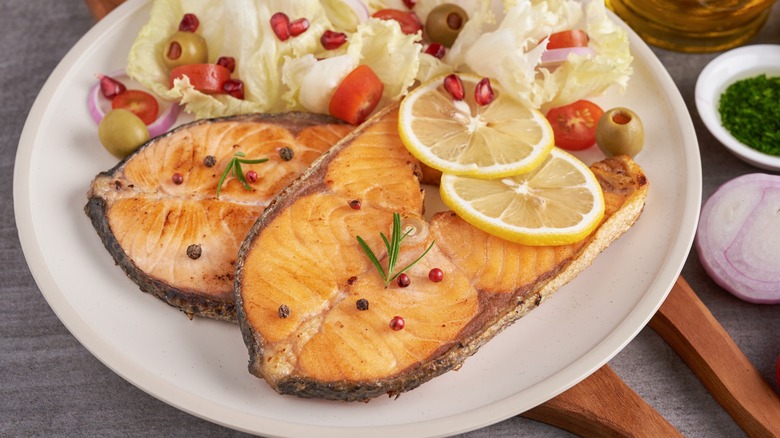 Cooked salmon steaks with lemon slices and sides
