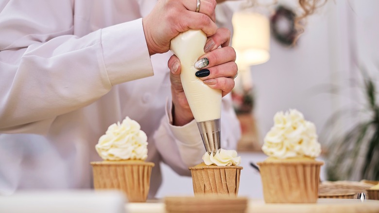 Piping icing onto finished cupcakes