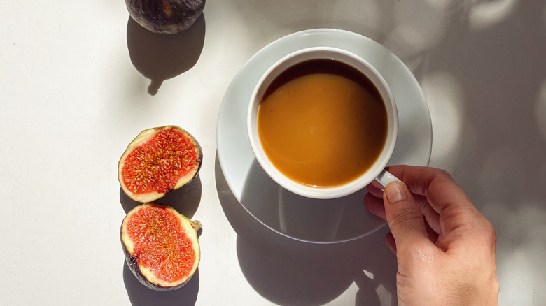 A cup of coffee next to whole and halved figs