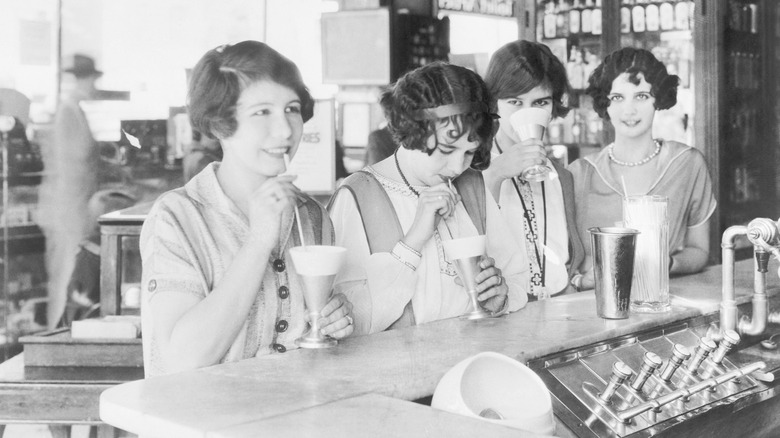 Women at a soda fountain drinking milkshakes