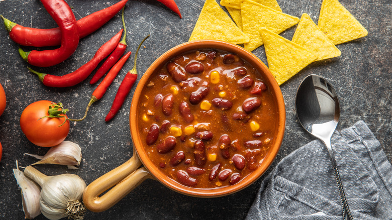 Chili with peppers, tortilla chips, tomato