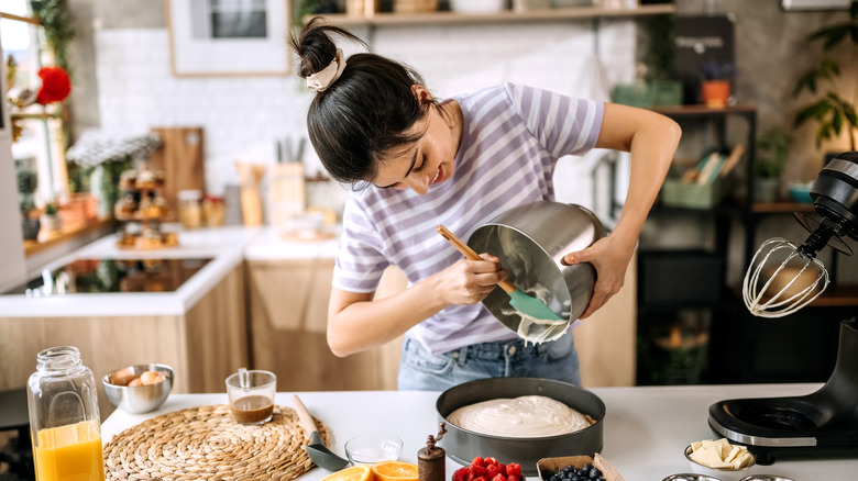 Woman pouring cake batter into pan