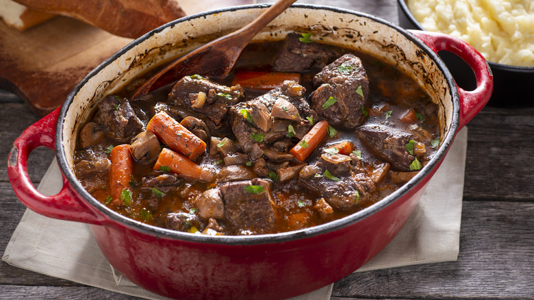 Beef stew with carrots in a pot with wooden spoon